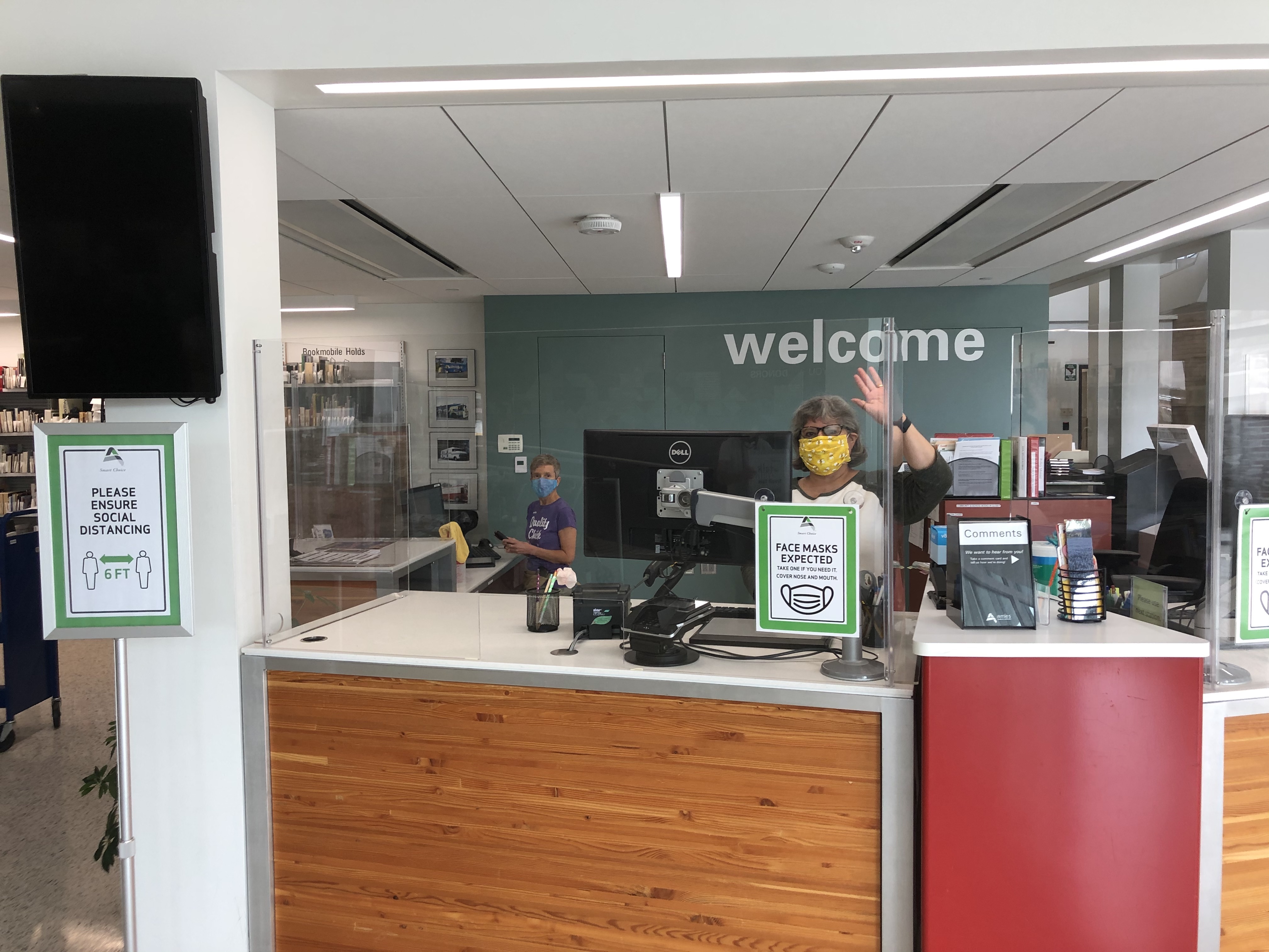 Ames Public Library Welcome Desk with waving staff member