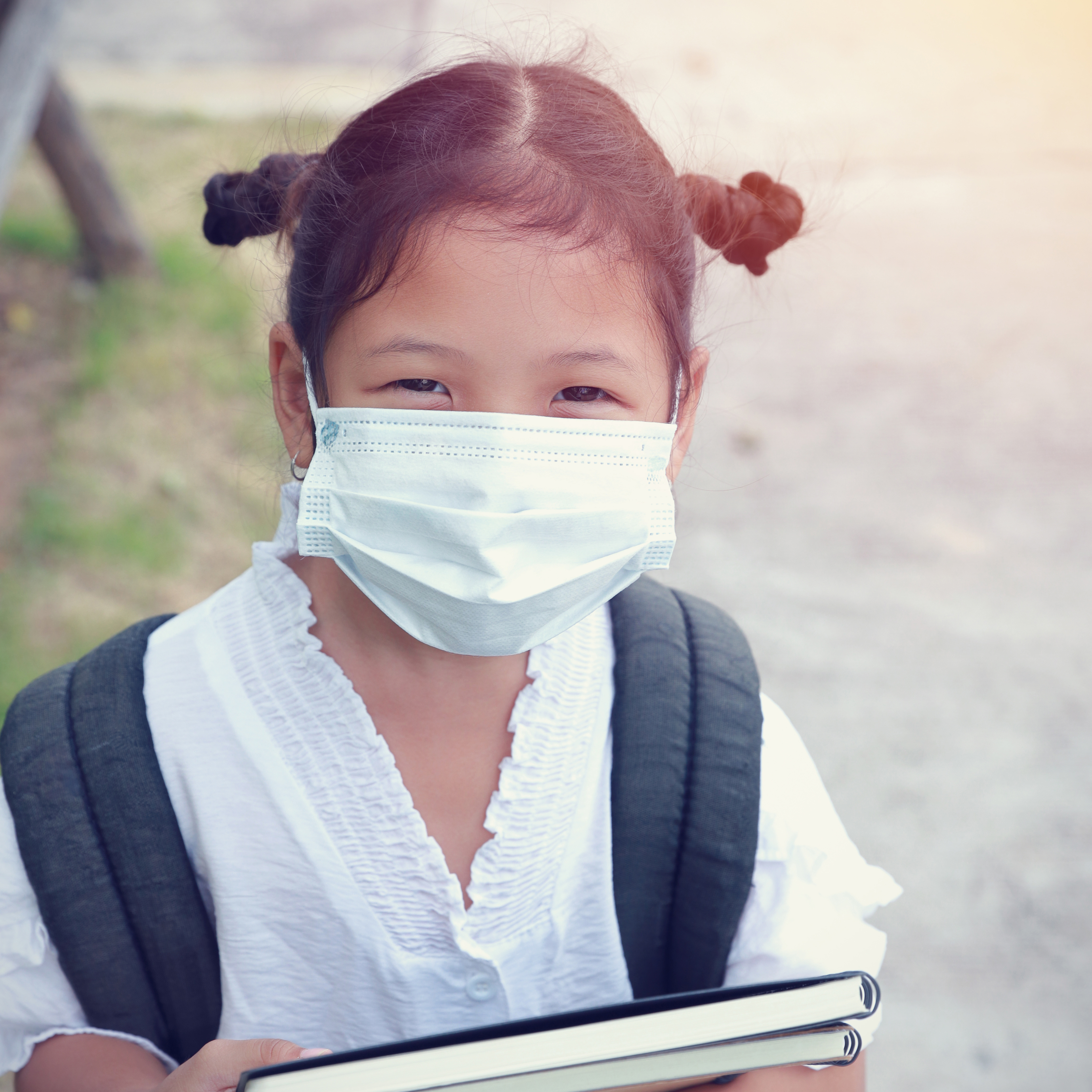 Girl with face mask holding books