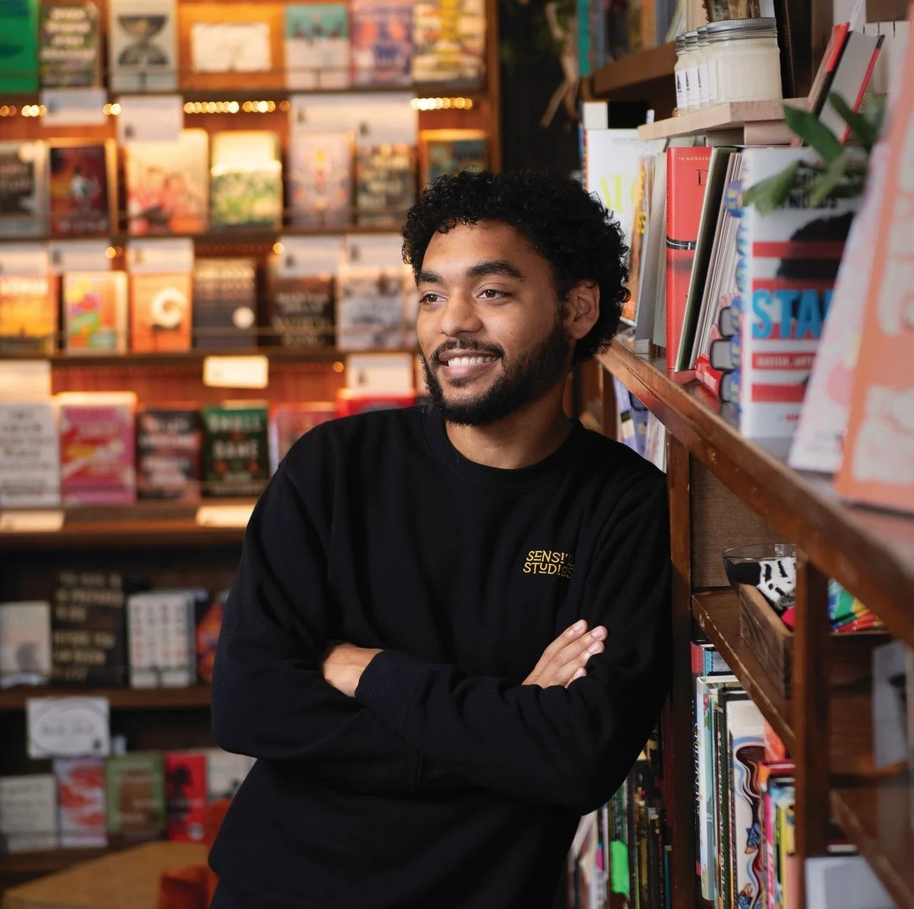 Photo Basi Affia leaning on book shelves. Photo by Duane Tinkey of DSM Magazine