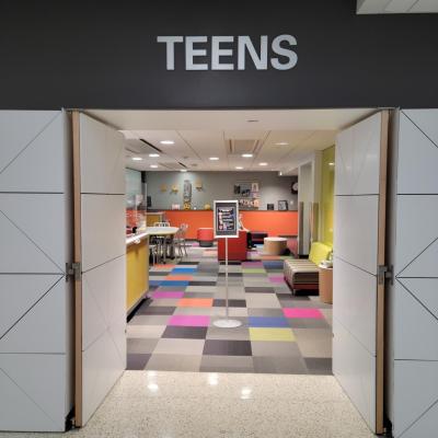 Photo of Ames Public Library's Teen Space with "TEENS" above doors and colorful room showing through doorway