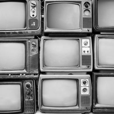 Black and white photo of old televisions stacked together