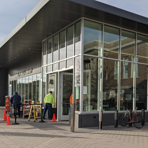 Front entry of Ames Public Library with crew working on replacement
