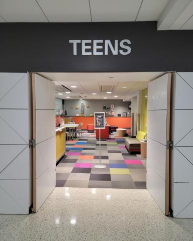 Photo of Ames Public Library's Teen Space with "TEENS" above doors and colorful room showing through doorway