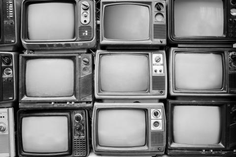 Black and white photo of old televisions stacked together