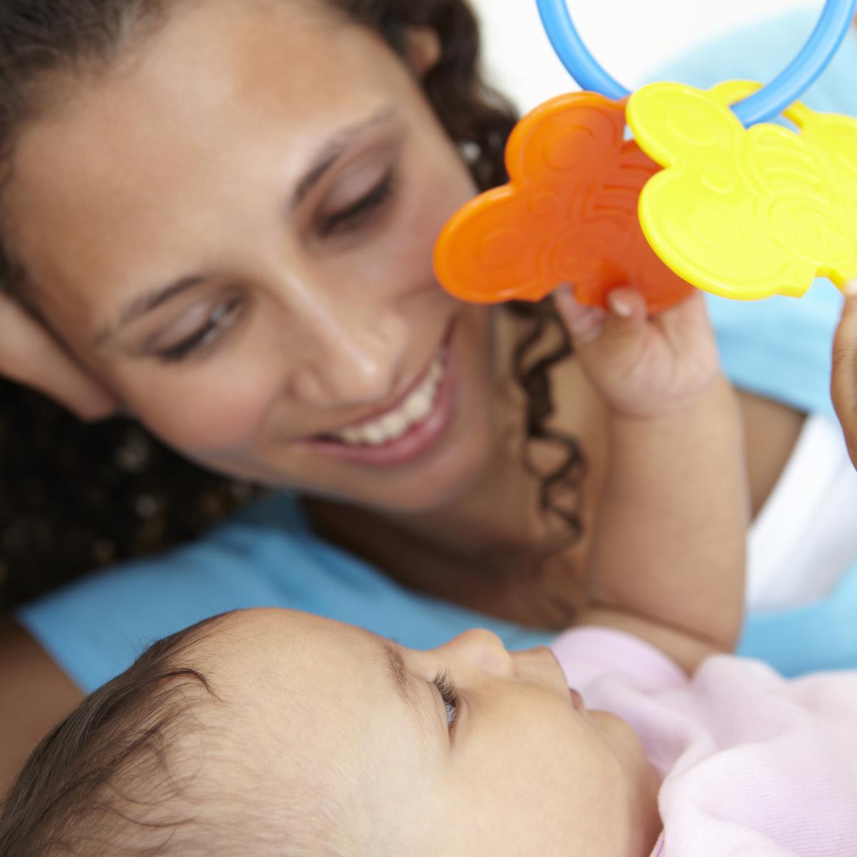 Mother watching while baby plays with toy